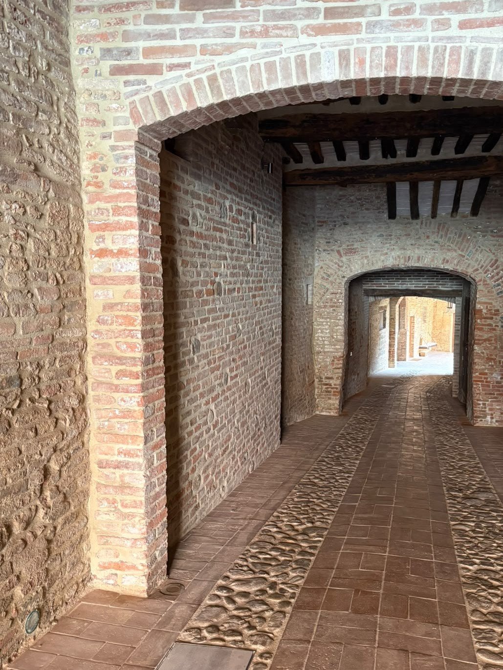 The entrance hall today, with the restored brick walls, the beamed ceiling and the terracotta and cobblestone floor