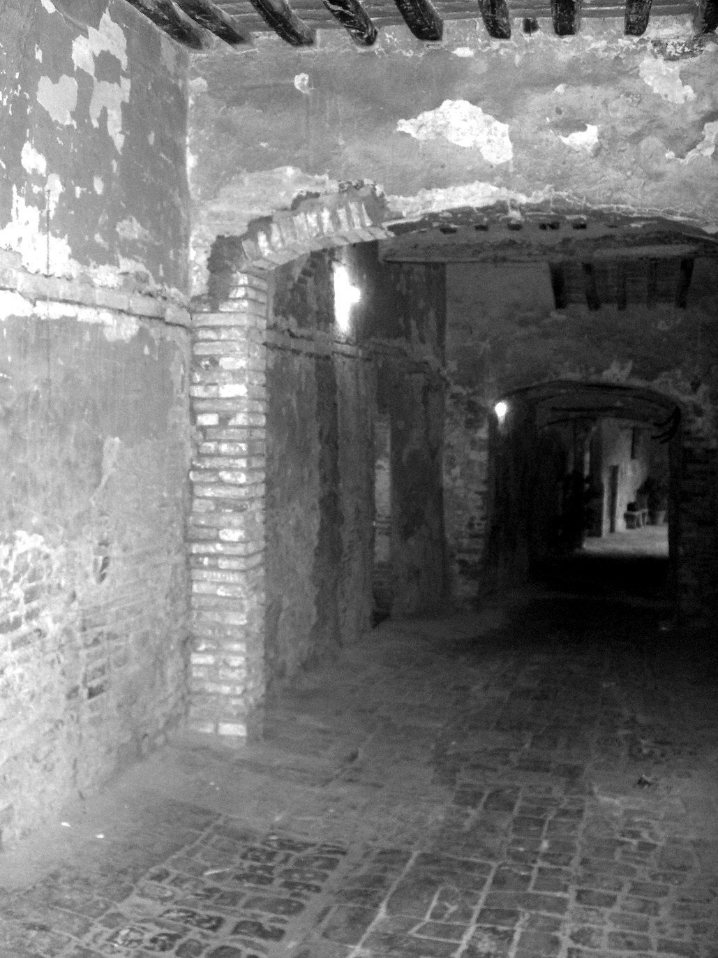 The same entrance hall before the works, dark, with the plaster flaking off and the floor damaged