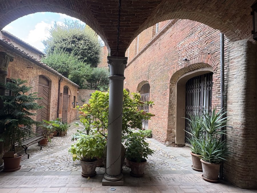 The portico with the stone column and the tree-lined courtyard