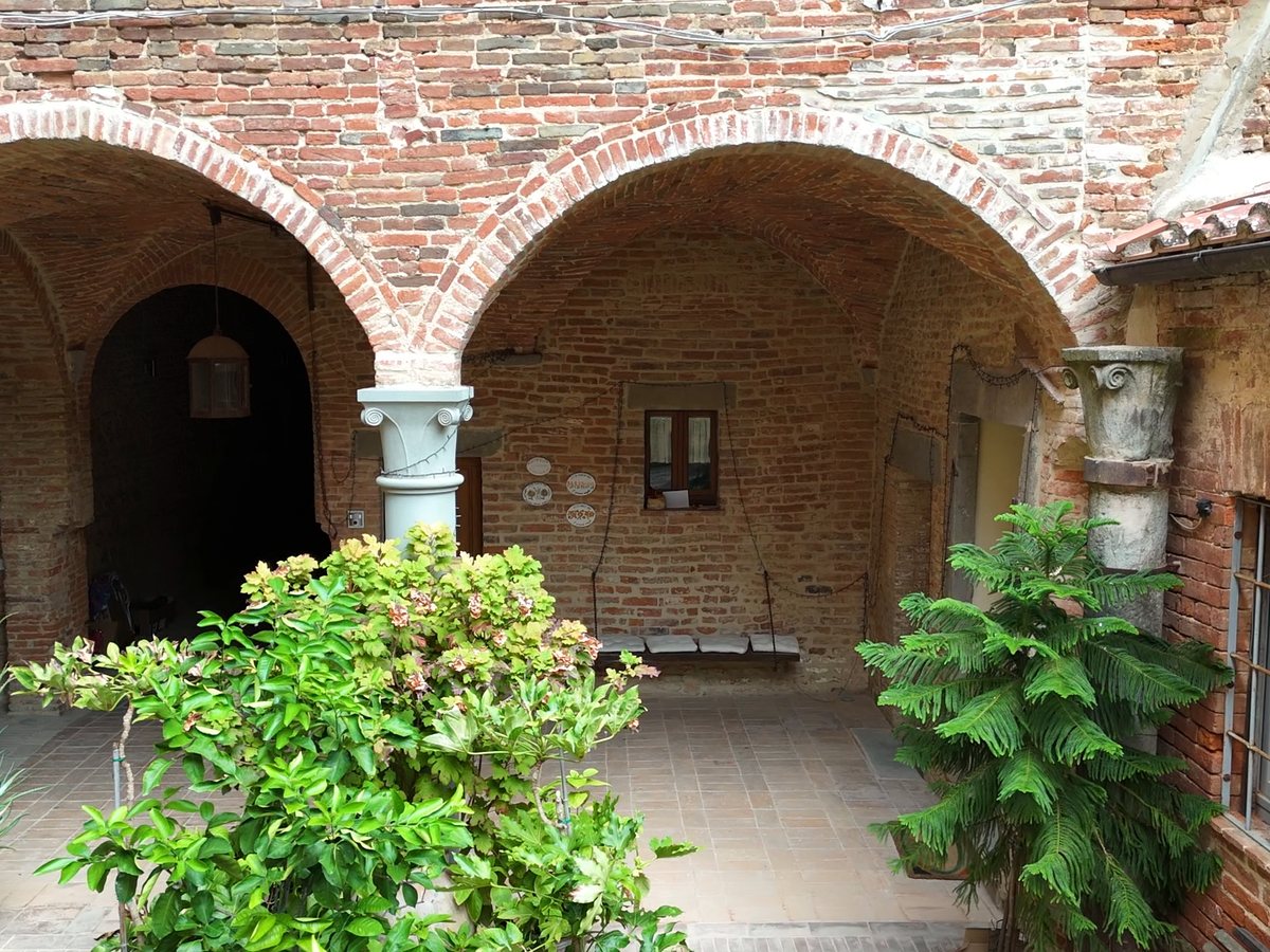 The loggia of Palazzo Bandini overlooking the courtyard, with brick arches and stone columns
