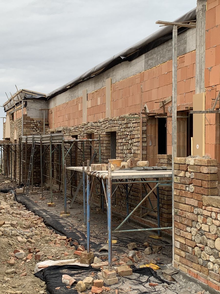 The low wing along the farmhouse with the new masonry and the scaffolding