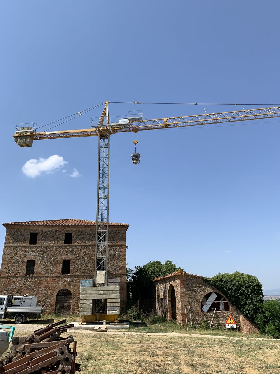 The tower crane beside the farmhouse and the old stable with the brick arch