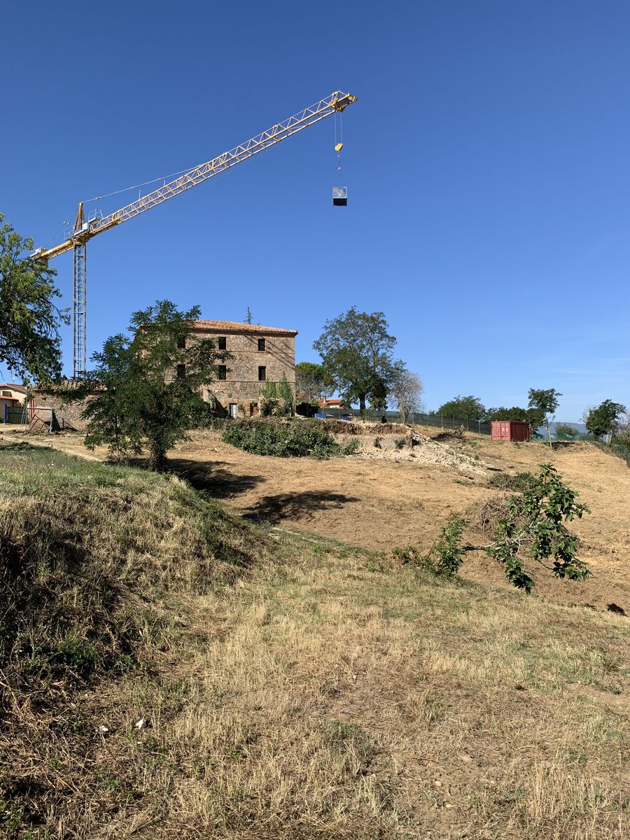 The farmhouse and the cleared land, with the crane at work