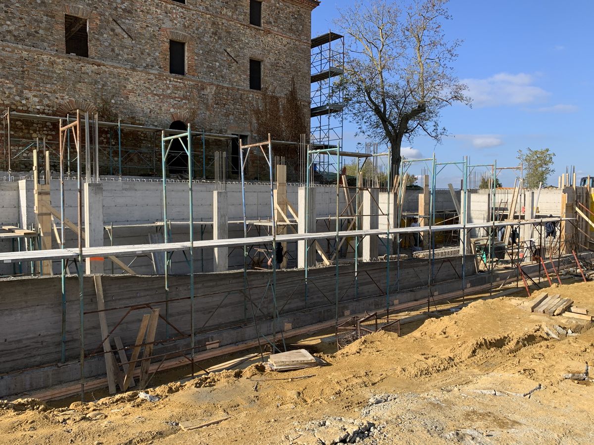 Reinforced concrete walls and scaffolding in the new wing beside the farmhouse