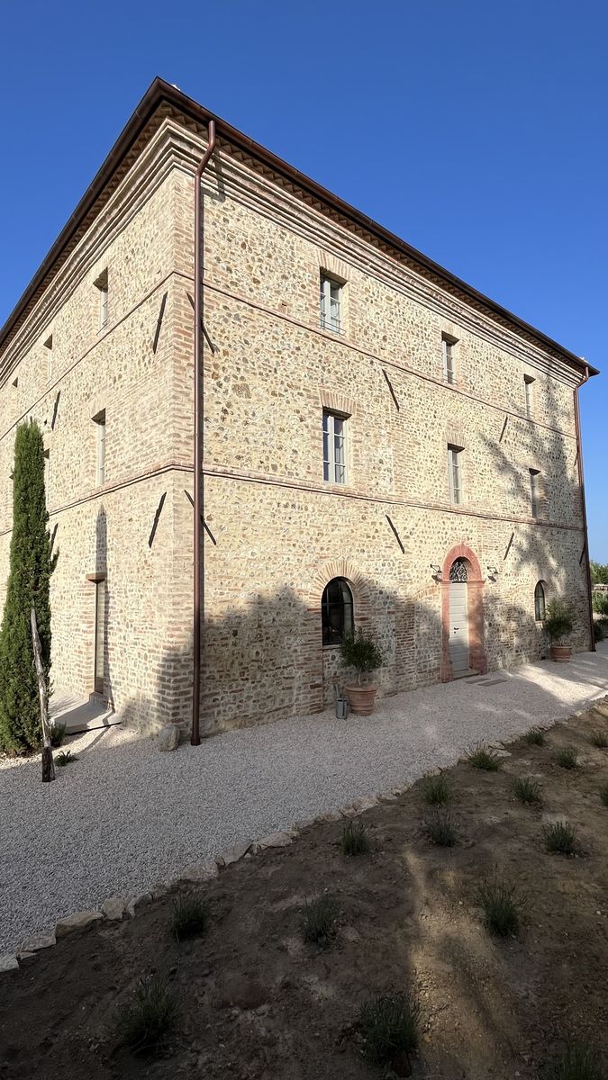 The restored stone farmhouse, seen from the corner, with the gravel path