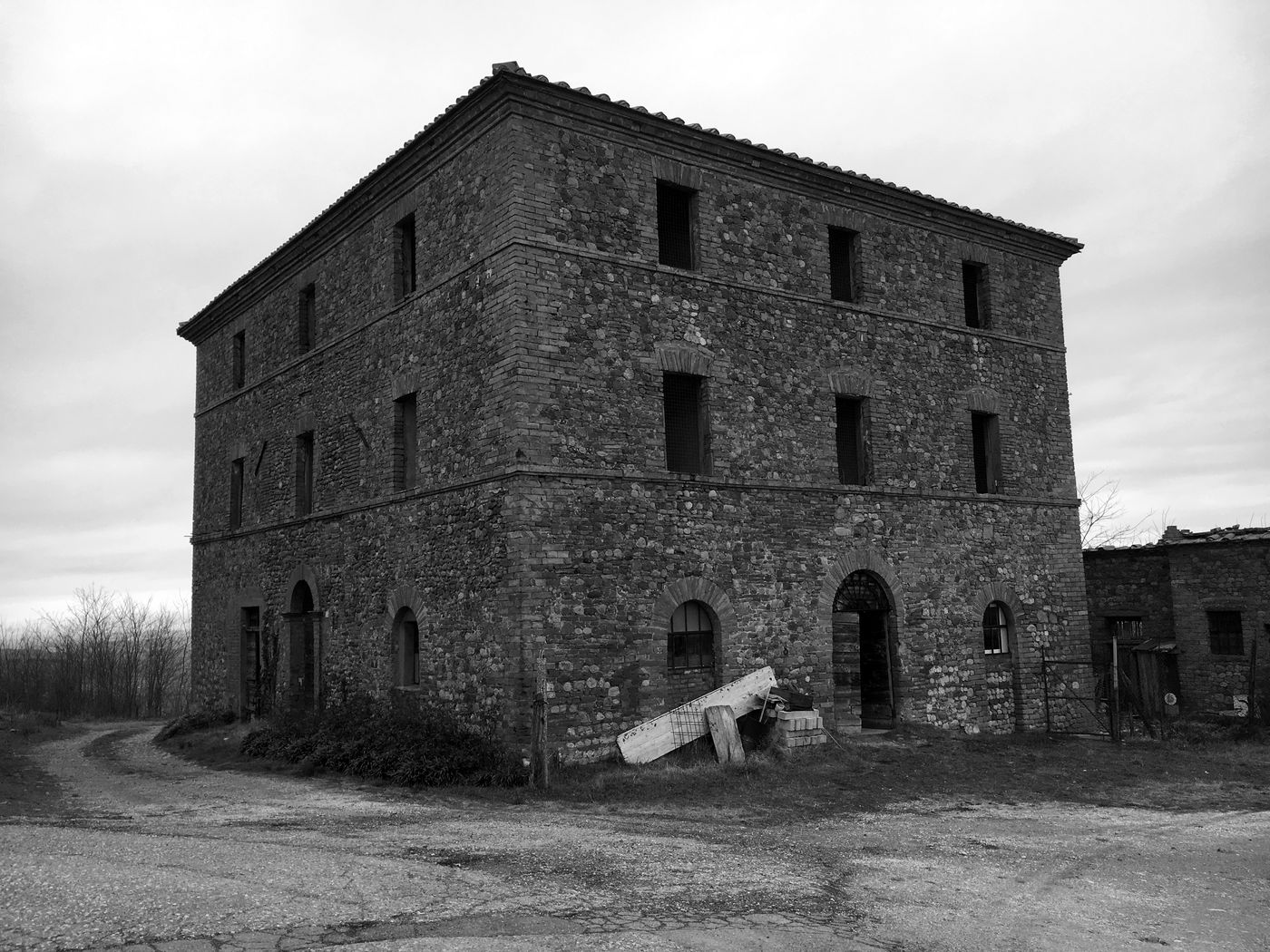 The stone and brick farmhouse before the restoration, with the outbuilding and the uncultivated land