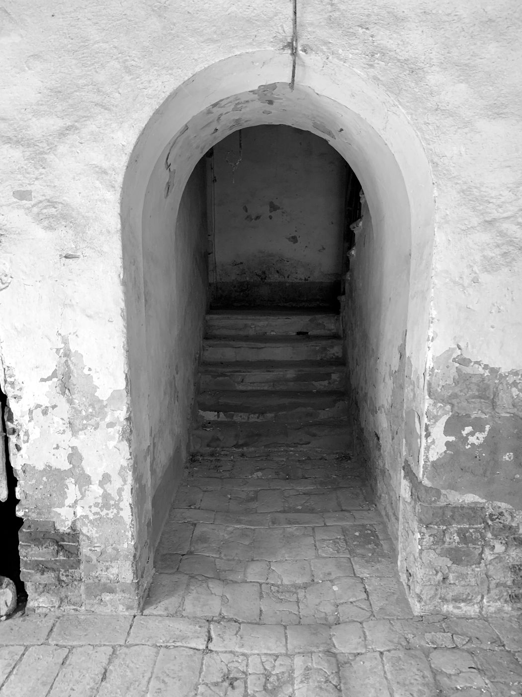 Stone staircase beneath an arch, with worn plaster