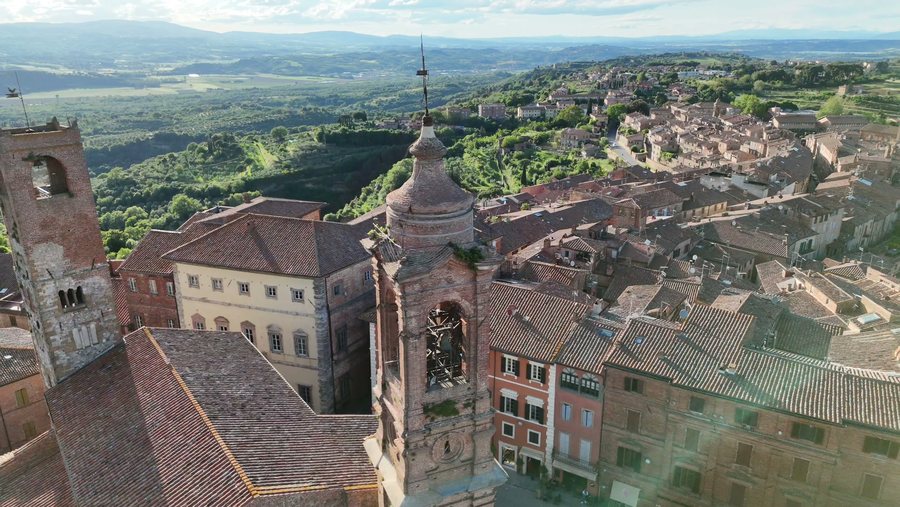Il campanile e i tetti in coppi accanto alla Cattedrale, con le colline sullo sfondo