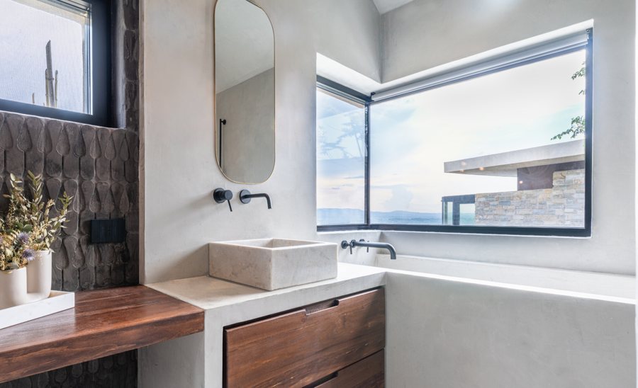 The bathroom with the stone basin and the corner window onto the landscape