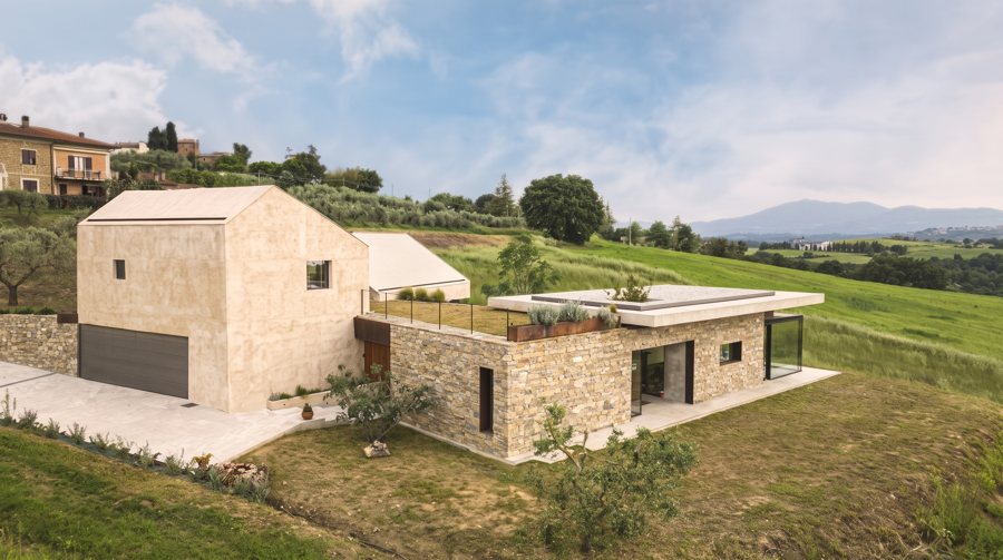 La Casa sul Chiaro seen from the lawn: the rendered volume with the garage and the stone wing with the roof garden