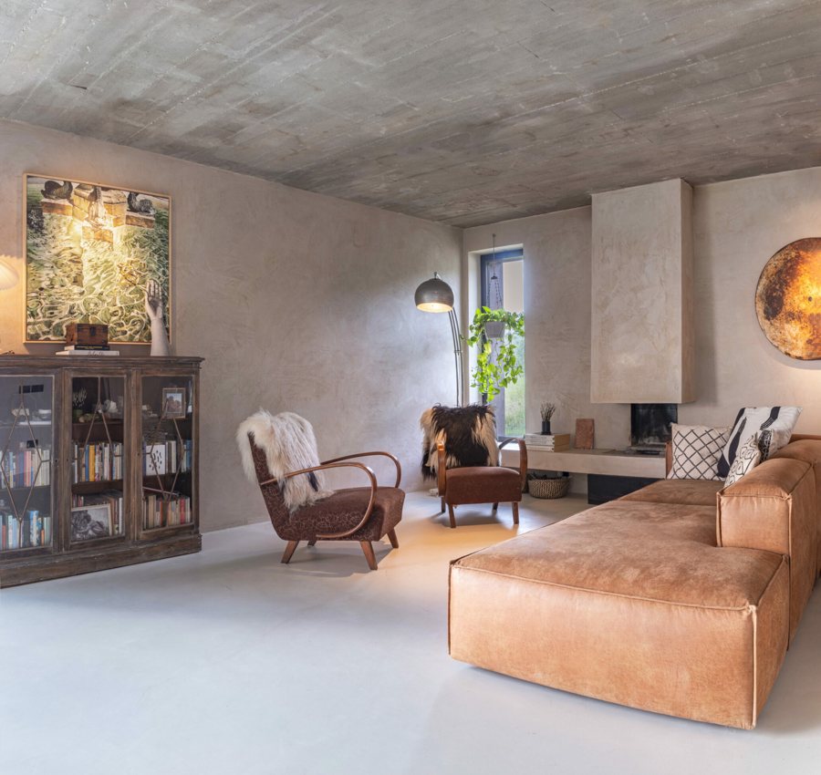 The sitting room with the fireplace, the exposed concrete ceiling and the leather sofa