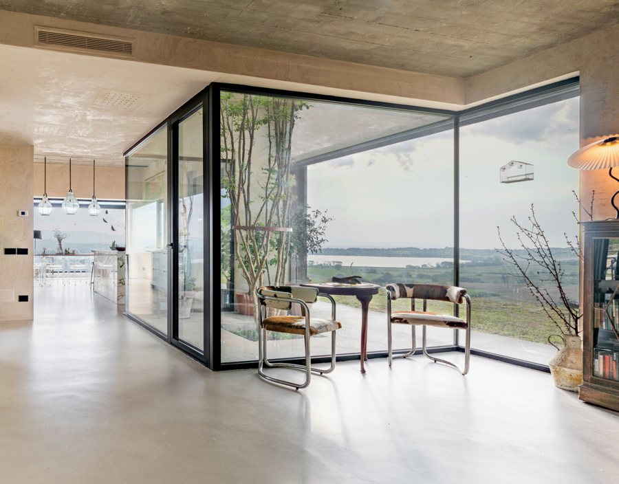 The glazed patio with the trees at the centre of the house and the view of the lake