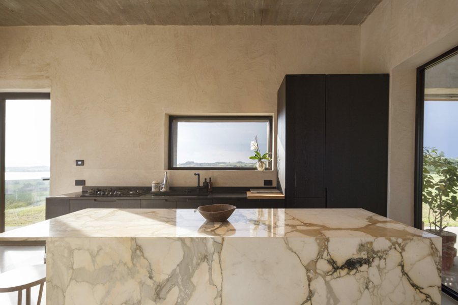 The living room with full-height windows opening onto the hills and Lake Chiusi
