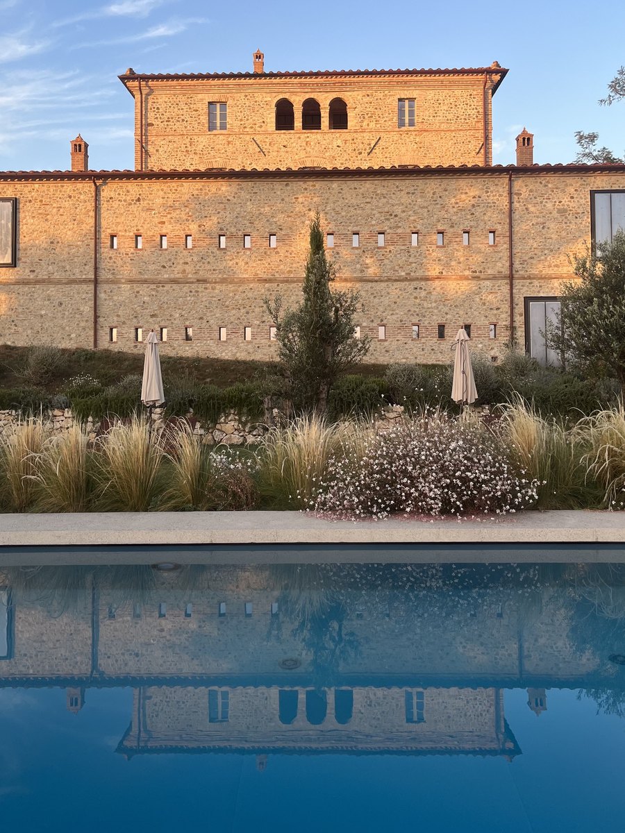 A restored stone building in the sunset light, with the garden and the pool