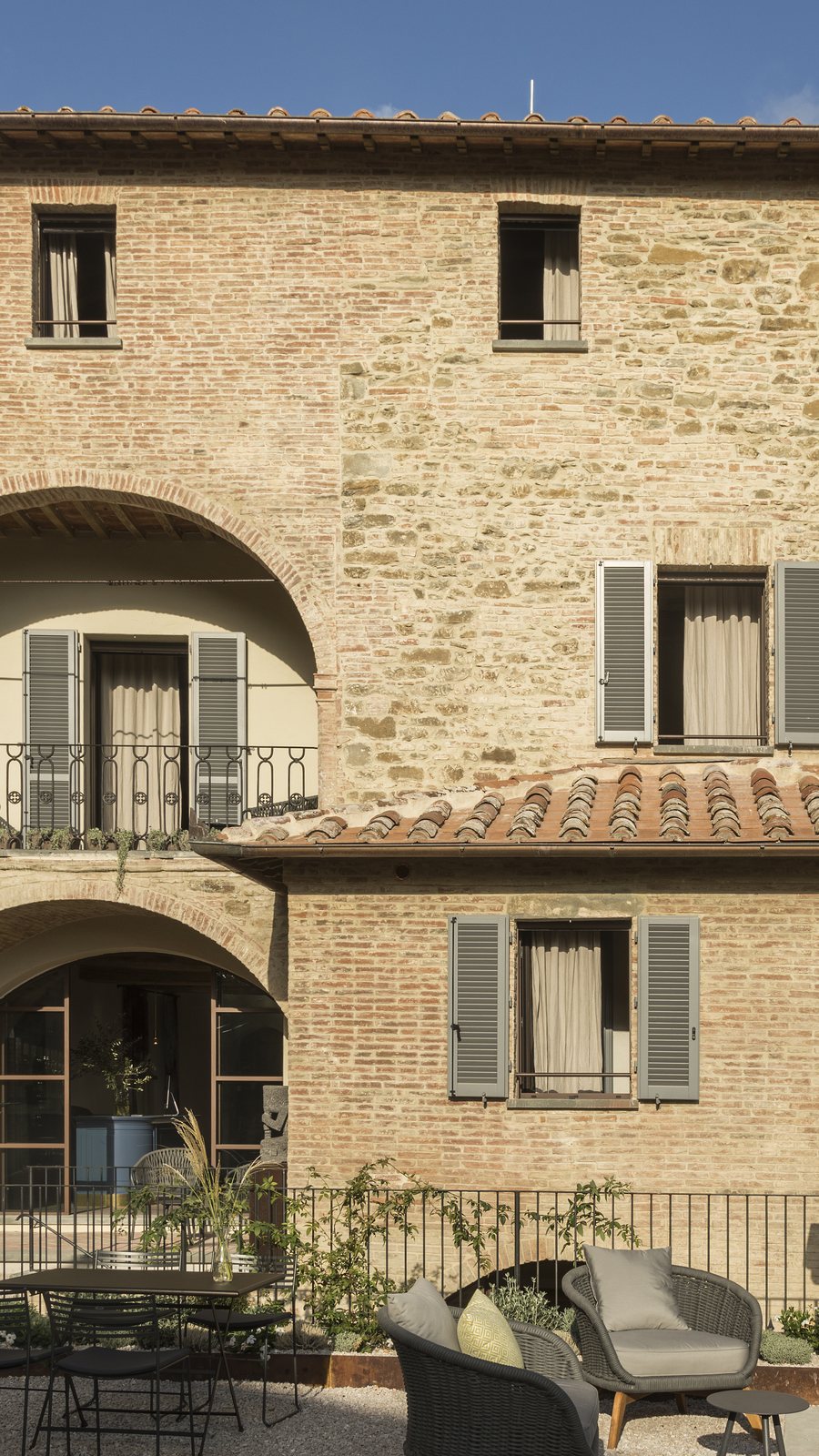 Stone and brick façade of Il Rastrello with the arched loggia over the garden