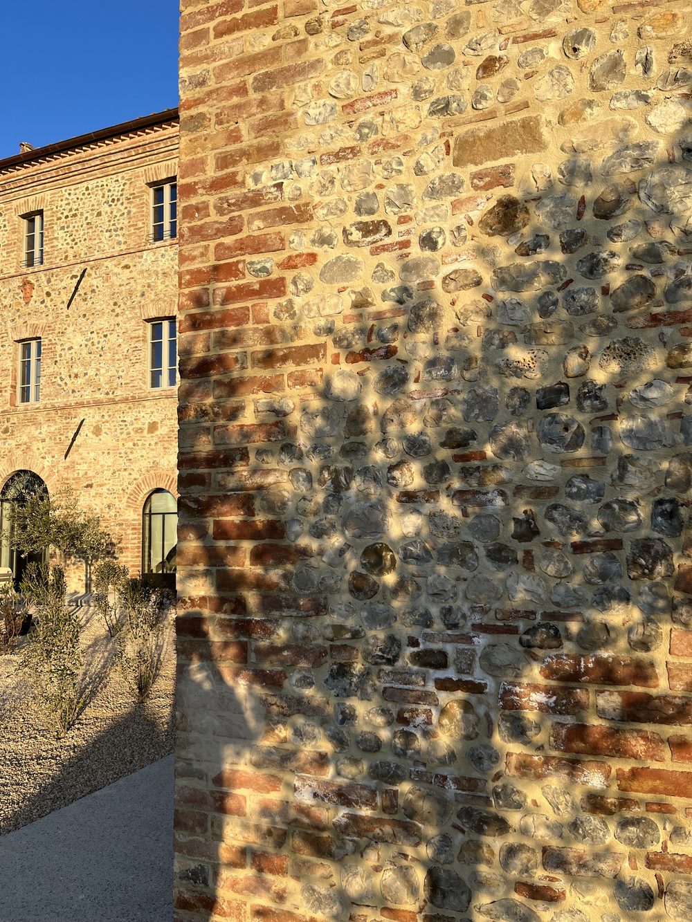 Stone and brick masonry at Ca' Litardo after the restoration, with the shadow of an olive tree