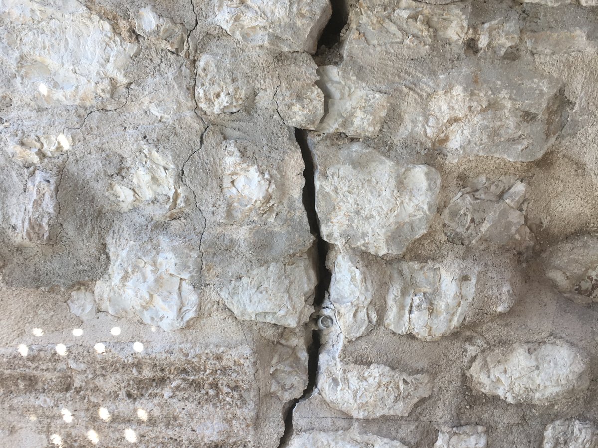 Una lesione profonda che attraversa la muratura in pietra del portale