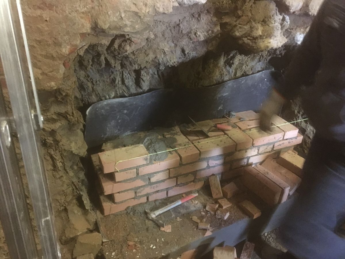 Muratura in mattoni in costruzione dentro un vano in pietra