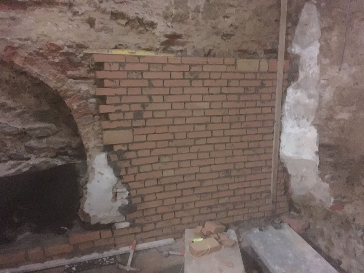 Arco in pietra con la nuova muratura in mattoni che chiude parte del vano
