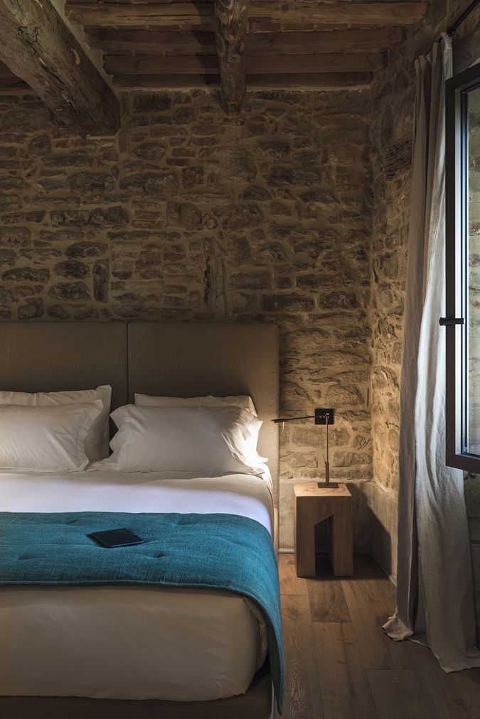 Camera Frantoio con muro in pietra a vista e letto con coperta turchese