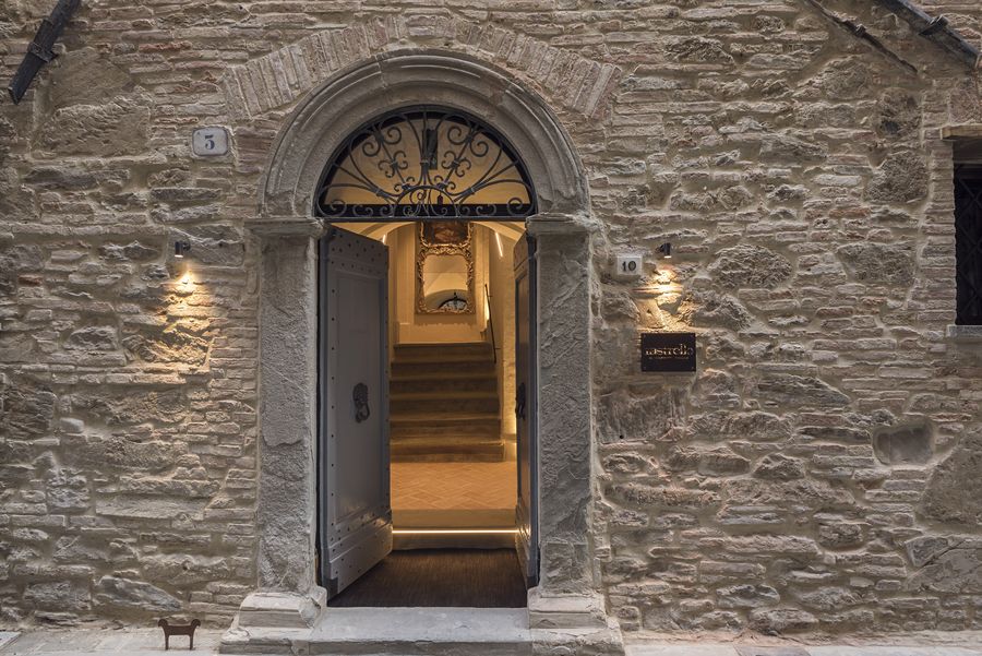Portale in pietra su via Grossi con la porta aperta sulla scala illuminata