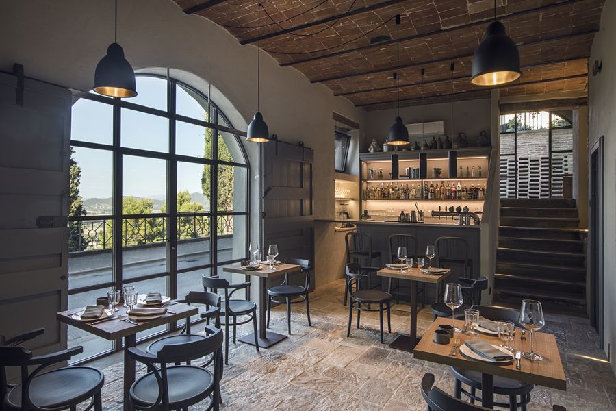 Ristorante con vetrate sulla valle, tavoli apparecchiati e scala in pietra