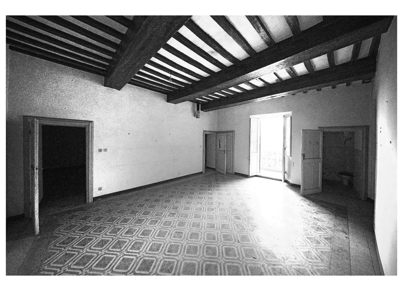 Stanza con pavimento in graniglia, soffitto a travi scure e porte in legno