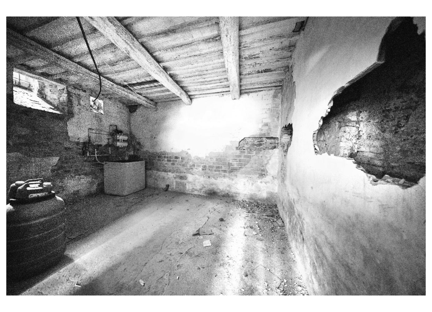 Stanza con il soffitto a travi e un grande distacco di intonaco sulla parete