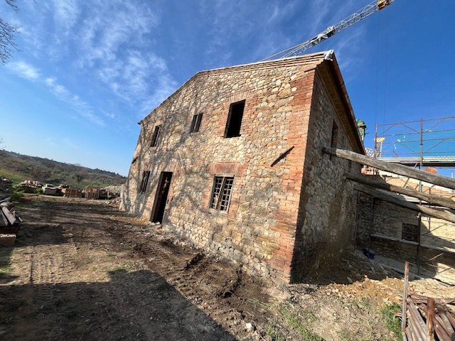 The side of the stone and brick farmhouse, with the crane