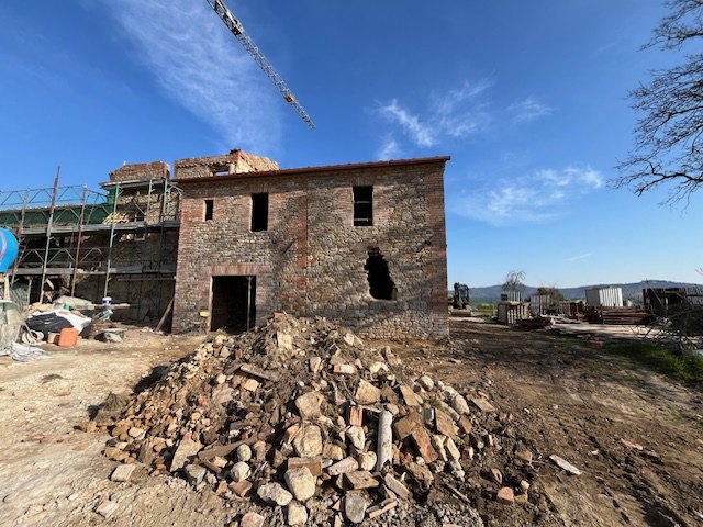 Stones from the collapsed walls, piled in front of an outbuilding