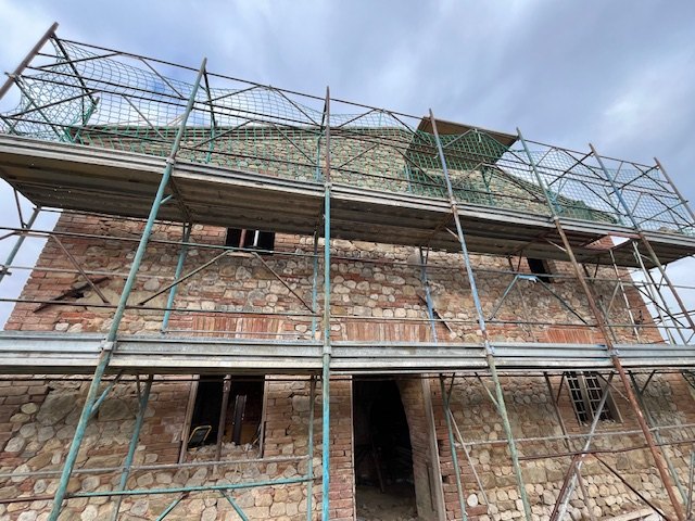 The house wrapped in scaffolding with the safety net on the roof
