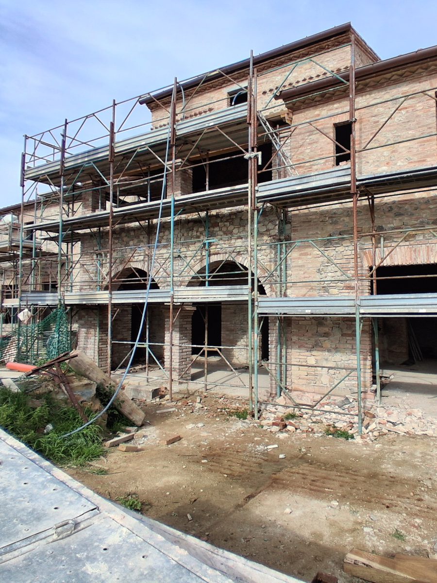 The Le Selve farmhouse under scaffolding, with the ground-floor arches and the stone and brick walls