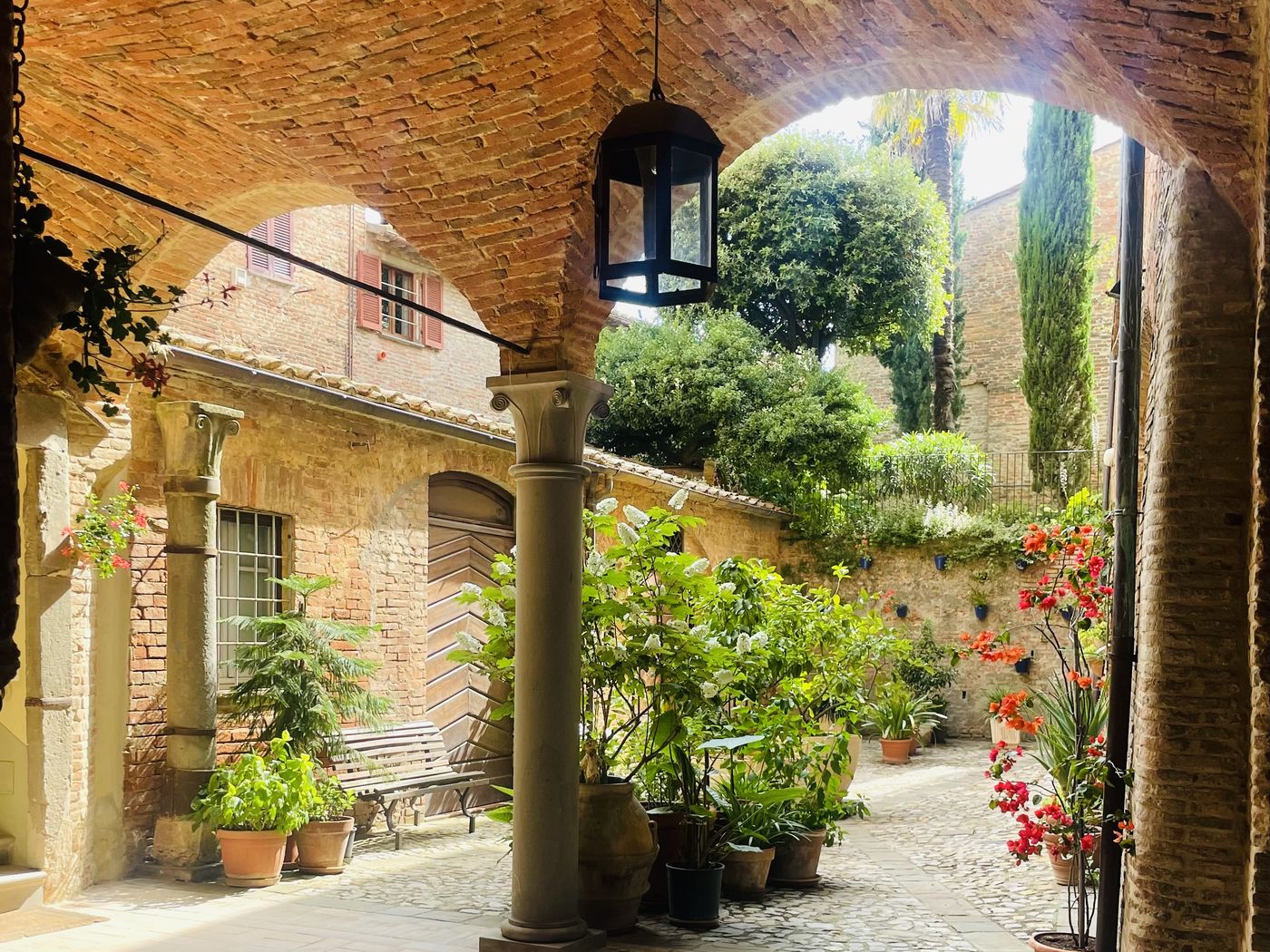 Entrance hall of Palazzo Bandini with a brick vault and a courtyard in flower