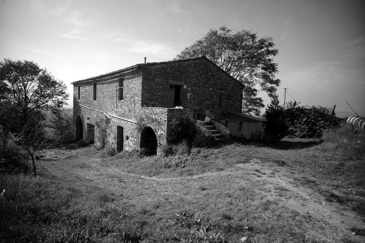 Il casolare prima dei lavori, con l’annesso ad arco e la scala esterna, tra l’erba alta